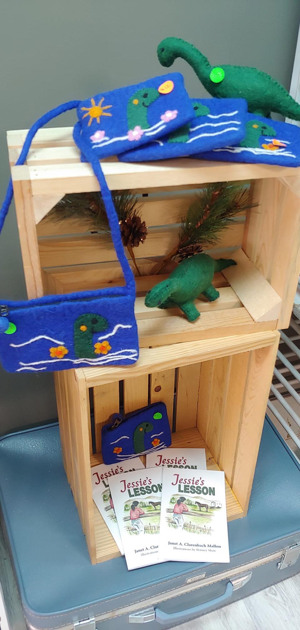 A shop display shows handcrafted stuffed animals of a green lake monster, as well as a purse and wallets.