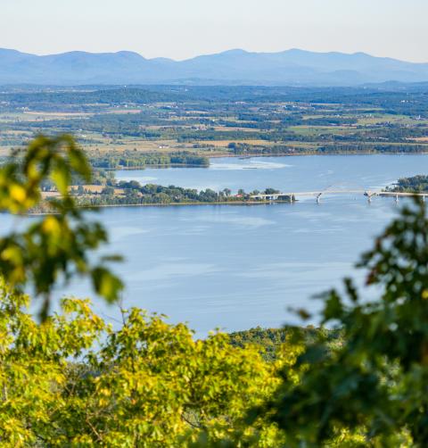 A lake framed by farmland and mountain ranges in the background. 