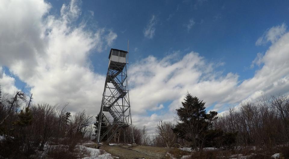 A tall steel firetower on a mountain