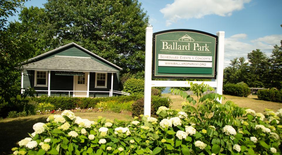 A sign for Ballard Park behind some white flowers