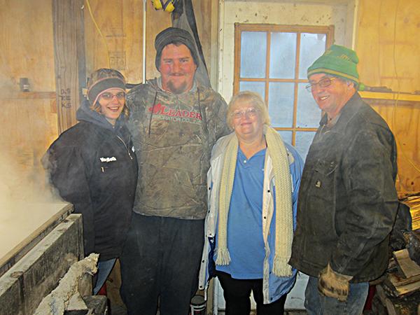 Two generations of the Sayre family smiling inside the sugar shack.