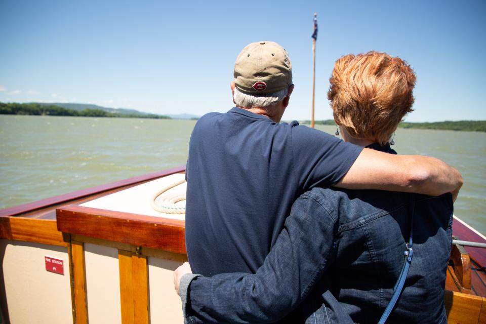 A couple aboard a tour boat, standing in the front looking at the shoreline view.