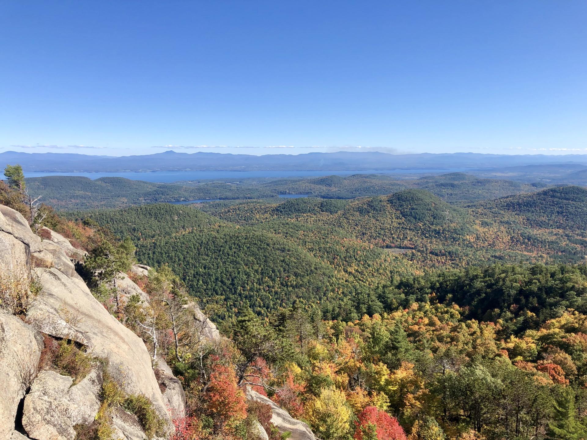 A rocky cliff looks over a colorful fall view