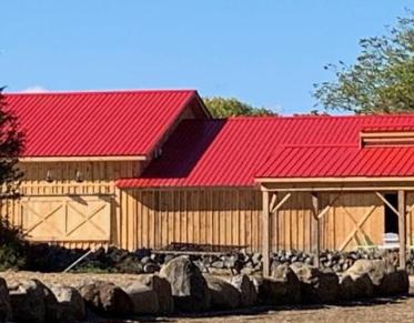 A wooden barn with red metal roof.