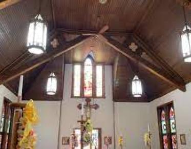Tall ceiling with stained glass windows and long drop lamps in the church.