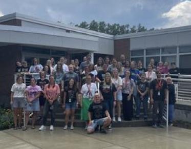 A group of people standing on the steps to a school.