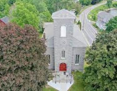 An aerial view of a tall stone church with red door.