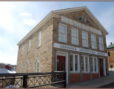 A tall stone building with white trim that houses the Adirondack Architectural Heritage.