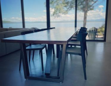 A dining table in place with a wall of floor to ceiling windows.
