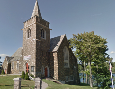 A tall stone church with high steeple on the banks of Mirror Lake.