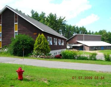 Exterior view of the lush grass and tall glass windows on the brown church.