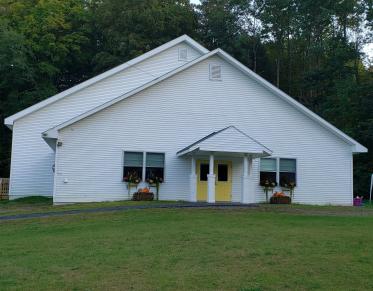 A white church with flower boxes and yellow doors.