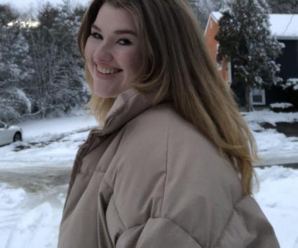 A woman smiles at the camera in a snowy image. 