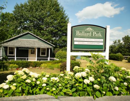 A sign for Ballard Park behind some white flowers