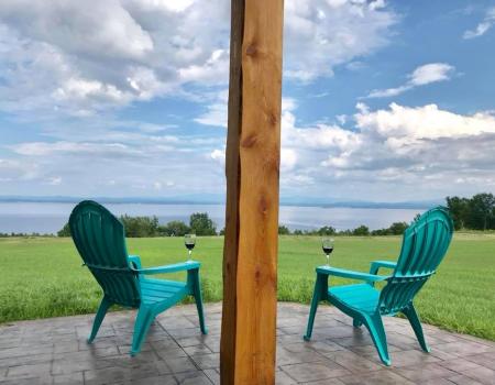 Two Adk chairs with wineglasses on arm overlooking Lake Champlain 