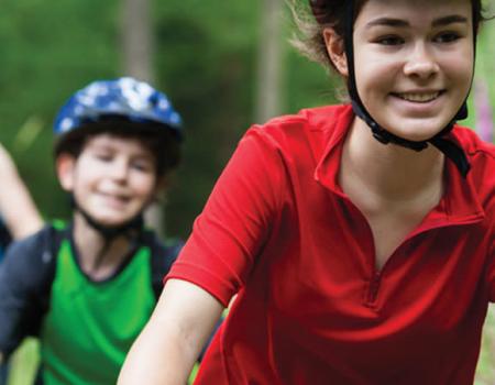 Smiling kids with helmets on bikes.