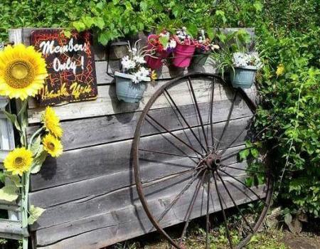 A wooden fence with flower planters hanging from the top with a sign reading members only