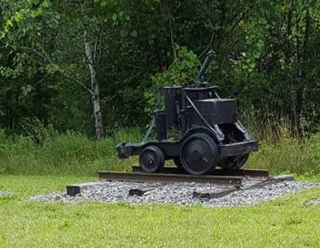 An old mine cart on display outdoors.