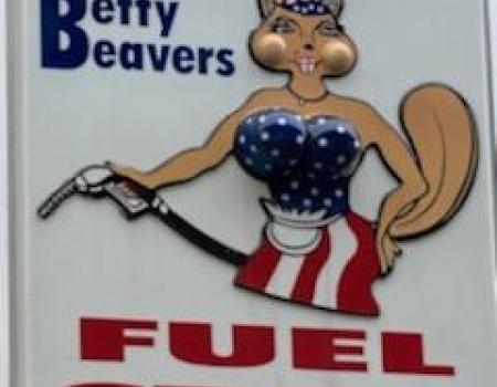 A large white sign with an illustrated beaver in a blue tube top and a white and red stripped skirt pumping gas.