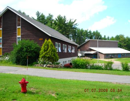 Exterior view of the lush grass and tall glass windows on the brown church.