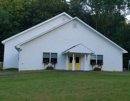 A white church with flower boxes and yellow doors.
