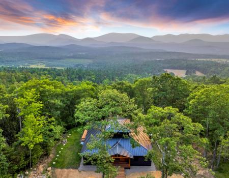 An aerial view of a new home with stunning view of the surrounding mountains and clouds.