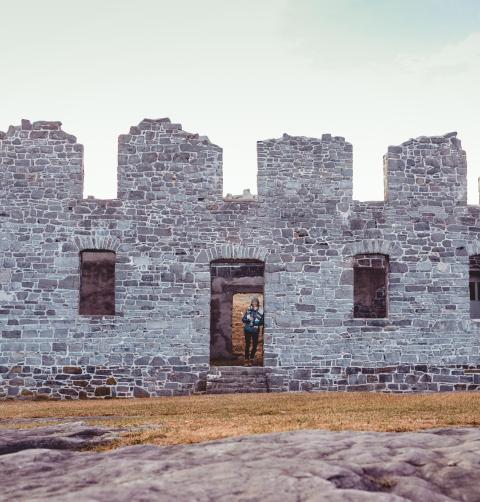 A person stands in a doorway of the ruins of Crown Point under a cloudy sky