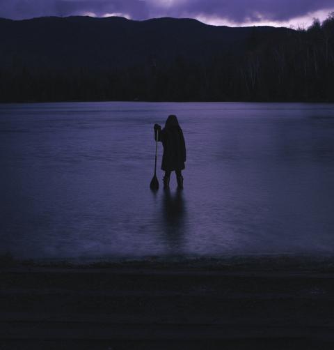 A figure appears to be emerging from a lake in the late twilight