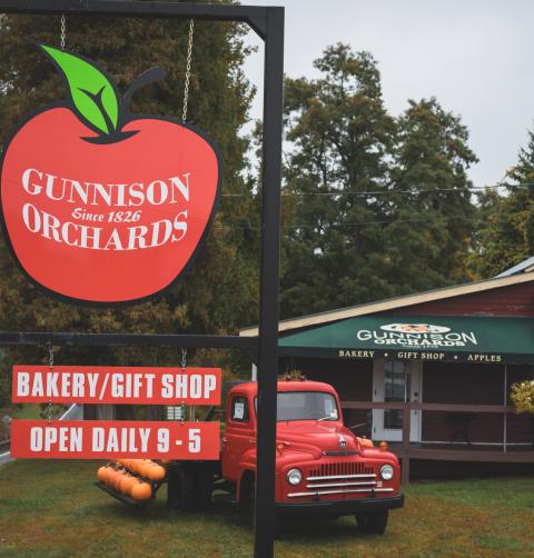 A farm store with an apple-shaped road sign for Gunnison Orchards. 