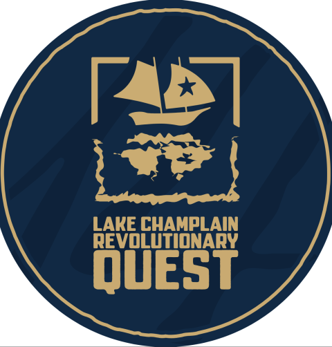 A circular graphic of navy blue, overlaid with a mustard-yellow logo and text. The logo is a sailing gunboat and the text reads Lake Champlain Revolutionary Quest.