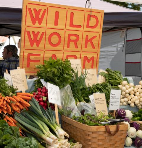A stand of fresh vegetables at a farmers market.