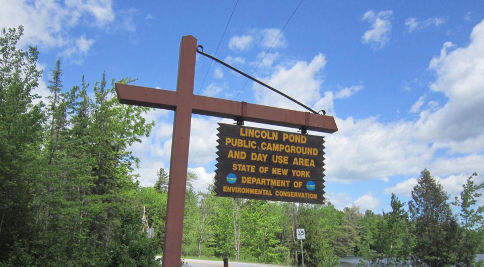 A yellow and brown sign marking a campground entrance.