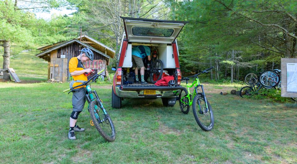 Two mountain bikers prep for a ride beside their vehicle