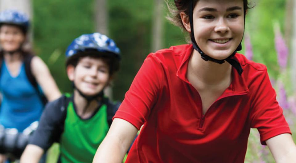 Smiling kids with helmets on bikes.
