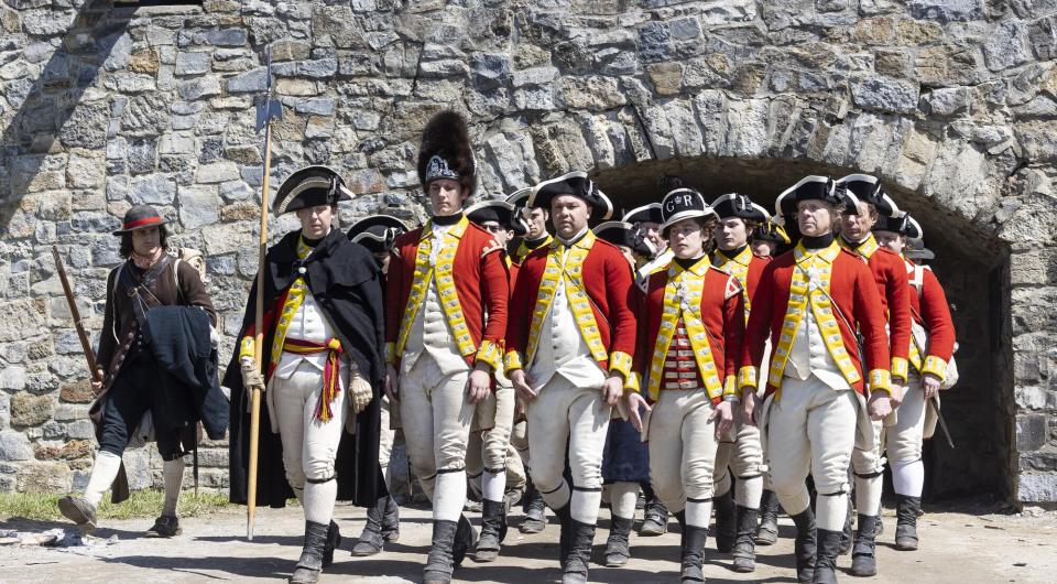 A kid wearing the tall black furry hat of the redcoats