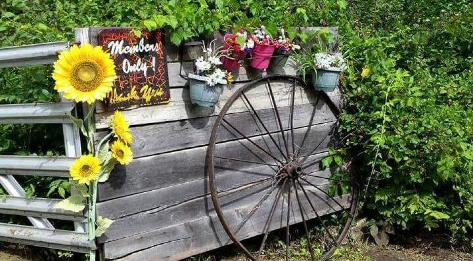 A wooden fence with flower planters hanging from the top with a sign reading members only