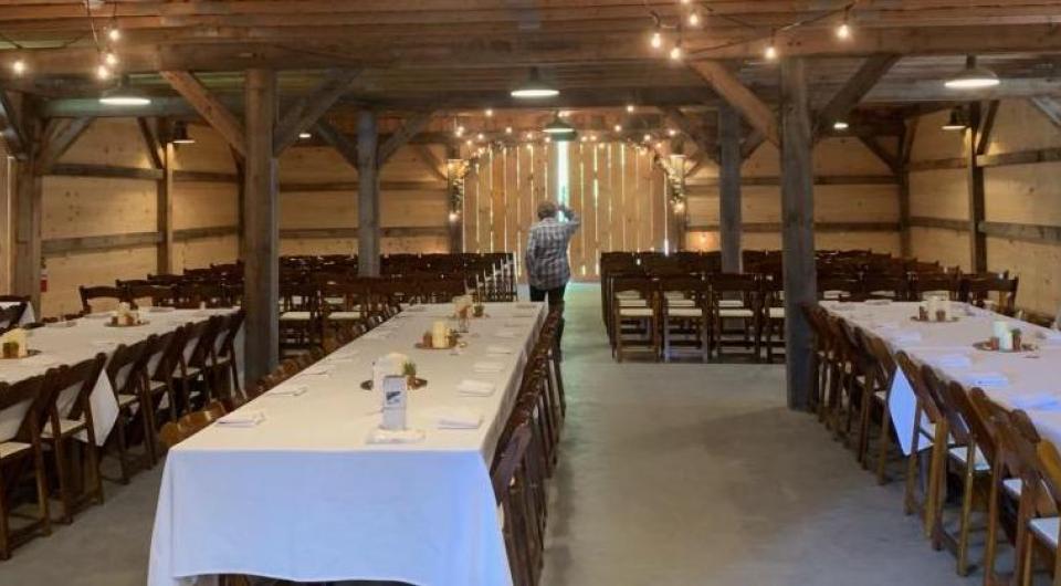 Long tables with white linens in the barn.