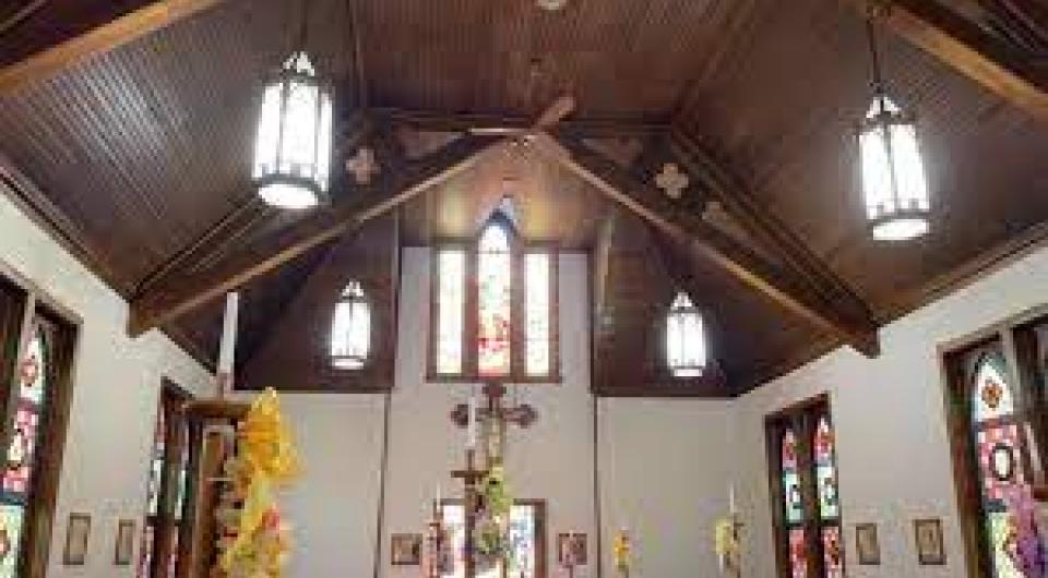 Tall ceiling with stained glass windows and long drop lamps in the church.