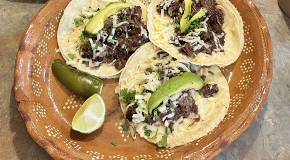 Three taco sit open faced on a plate.
