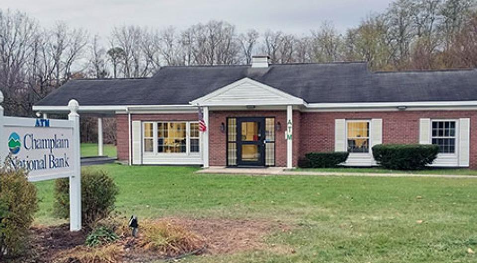 A squat brick building with white trim and covered entry way with large lawn.