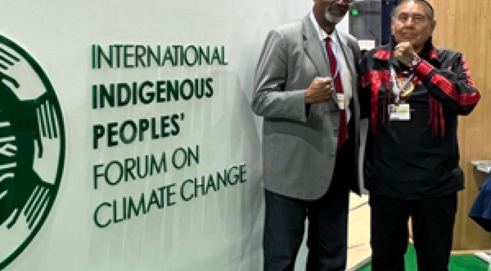 People standing in front of the International Indigenous Peoples Forum on Climate Change sign.