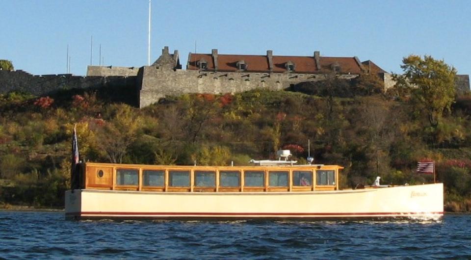 A view from the water looking at the side of the Carillon boat with the wall of Fort Ticonderoga behind it.
