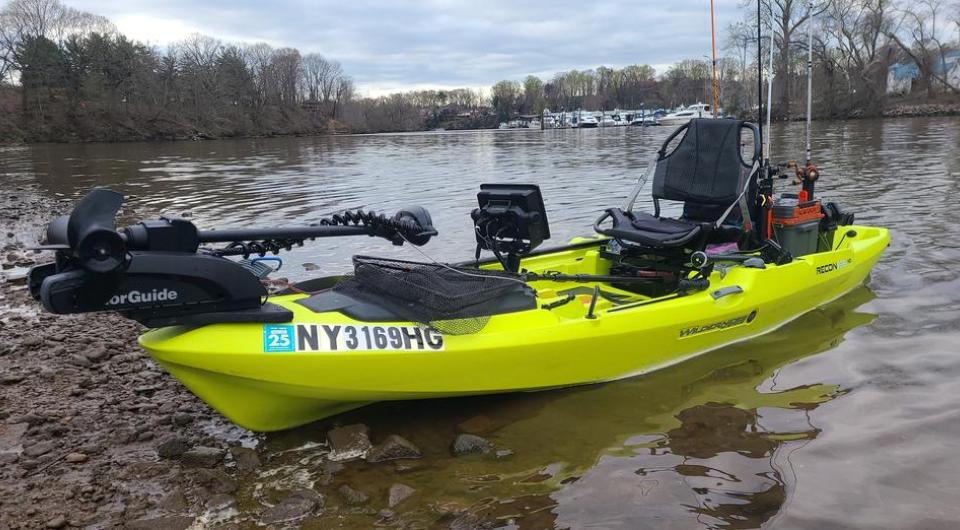 A green kayak fully fitted out with comfortable seat and fishing equipment.