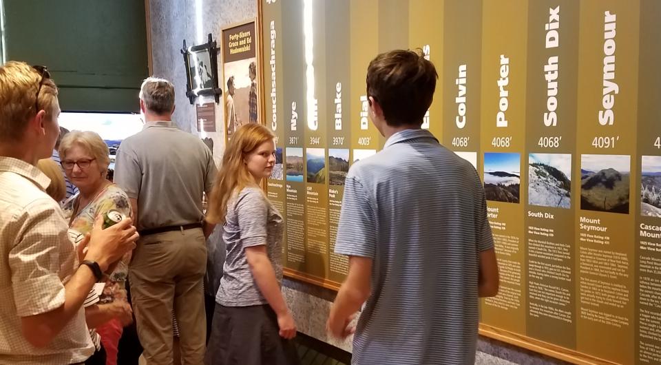 People look at a display discussing the high peaks.