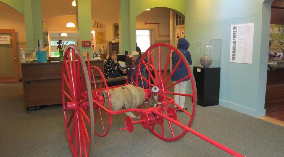 A red fire hose reel on large wagon wheels.