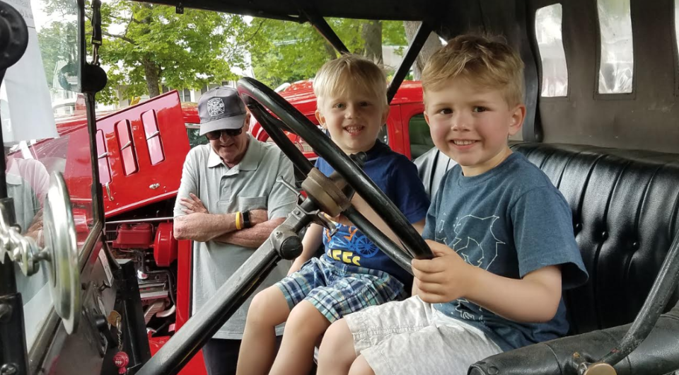 Smiling kids hold the steering wheel on equipment