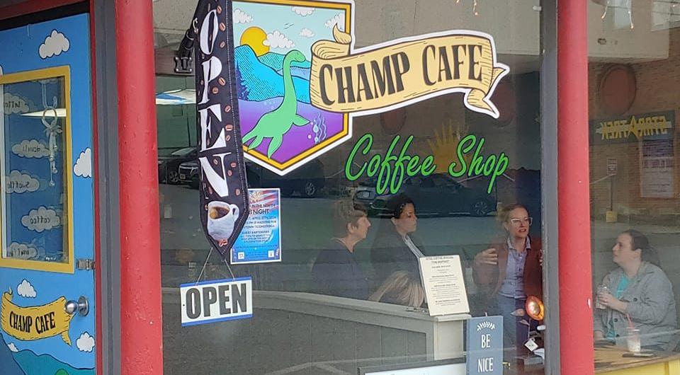 The exterior window art at the Champ Cafe with happy patrons at a table inside.