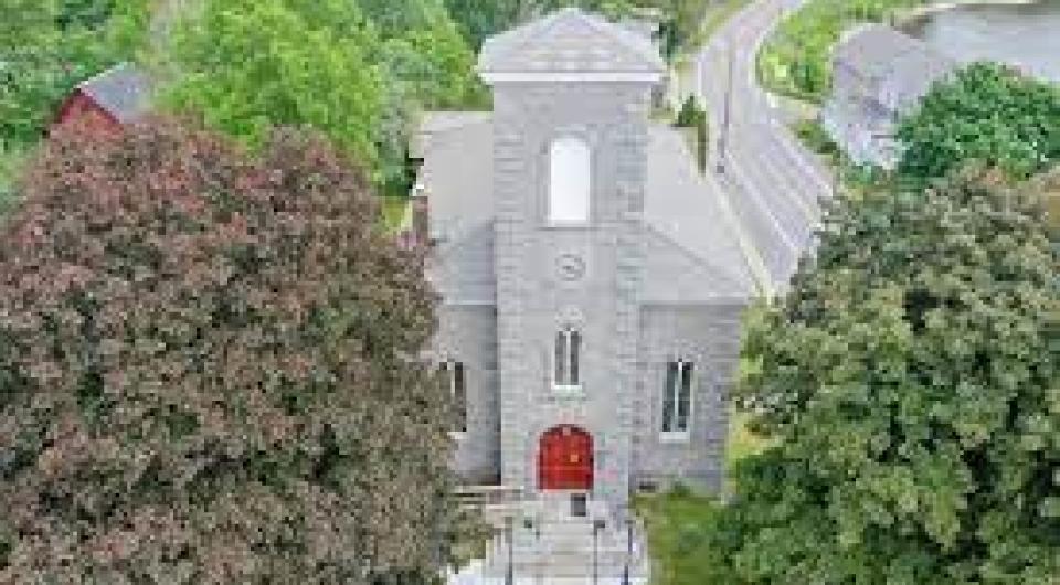 An aerial view of a tall stone church with red door.