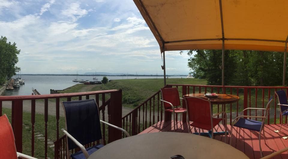 A covered porch with tables and chairs overlooking the marina.