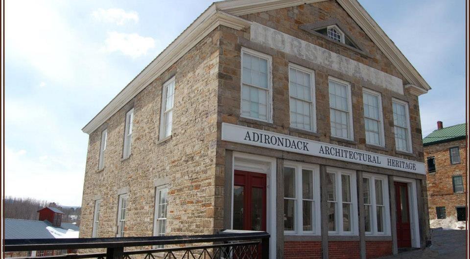 A tall stone building with white trim that houses the Adirondack Architectural Heritage.